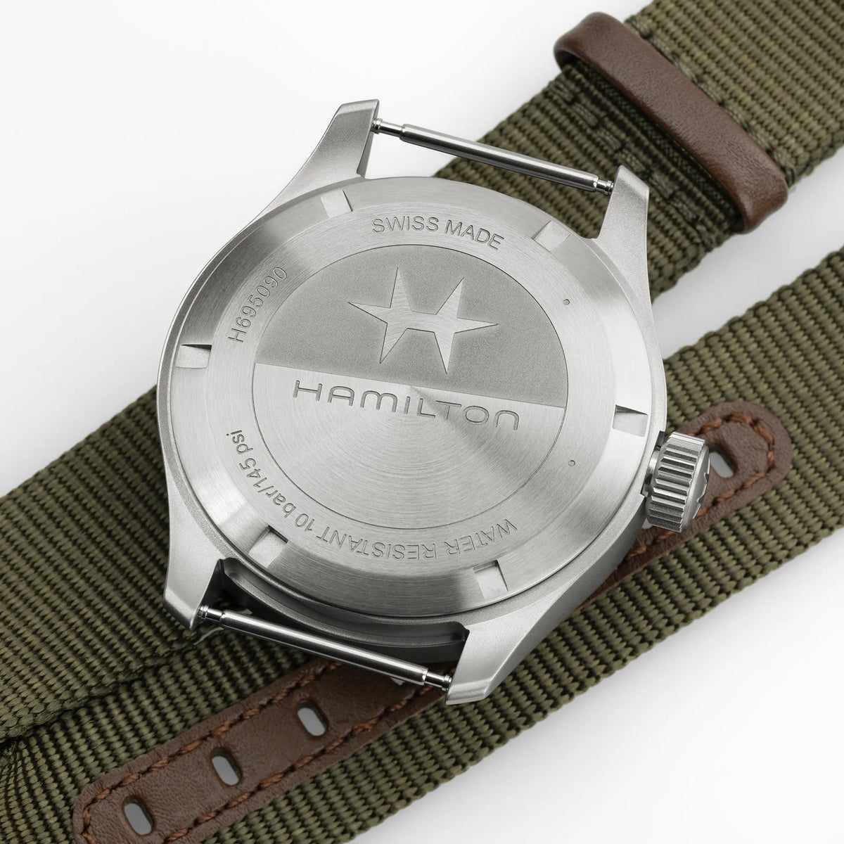 Produktfotografie zeigt den verschraubten Gehäuseboden des Uhrenkopfes von der Hamilton Khaki Field Powerreserve H69509960 mit olivgrünem Zifferblatt am Hamilton-typischen olivgrünen Nato-Armband
