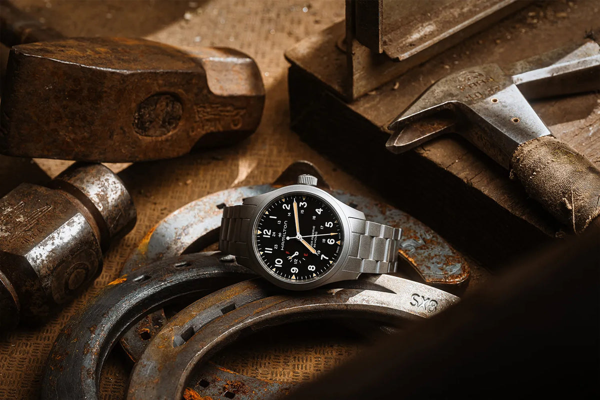 Fotografie der Hamilton Khaki Field Mechanical Power Reserve mit schwarzem Zifferblatt, während die Uhr in einer Metal-Schmiede liegt