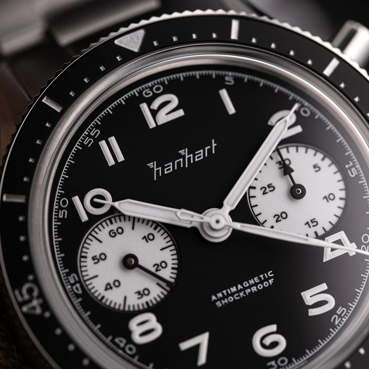 Detailaufnahme des Hanhart 415 ES Chronographs mit dem Reverse-Panda-Zifferblatt in Schwarz mit weißen Sub-Dials am Edelstahlarmband