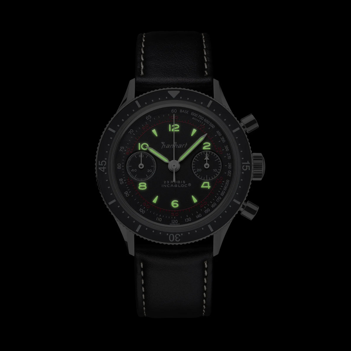 Frontale Ansicht des Hanhart 415 ES Pure Chronographen in Edelstahl mit weißen und roten Details am Lederband bei Nacht mit leuchtenden Zeigern und Indizes