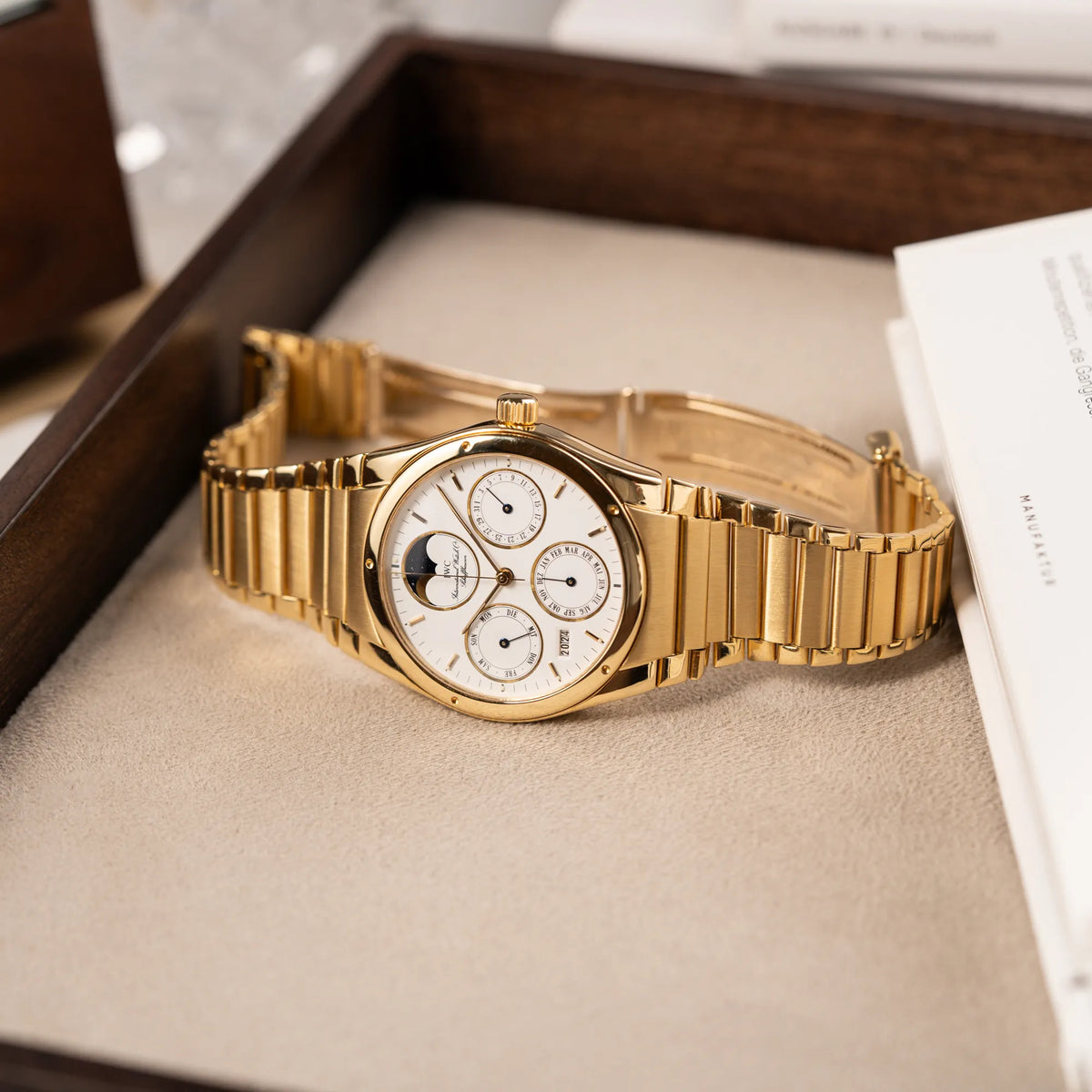 Produktfotografie der IWC Ingenieur Perpetual Calendar in Gelbgold mit weißem Zifferblatt und zughörigem Gelbgold-Armband, während die Uhr auf einem Juwelierstablet liegt