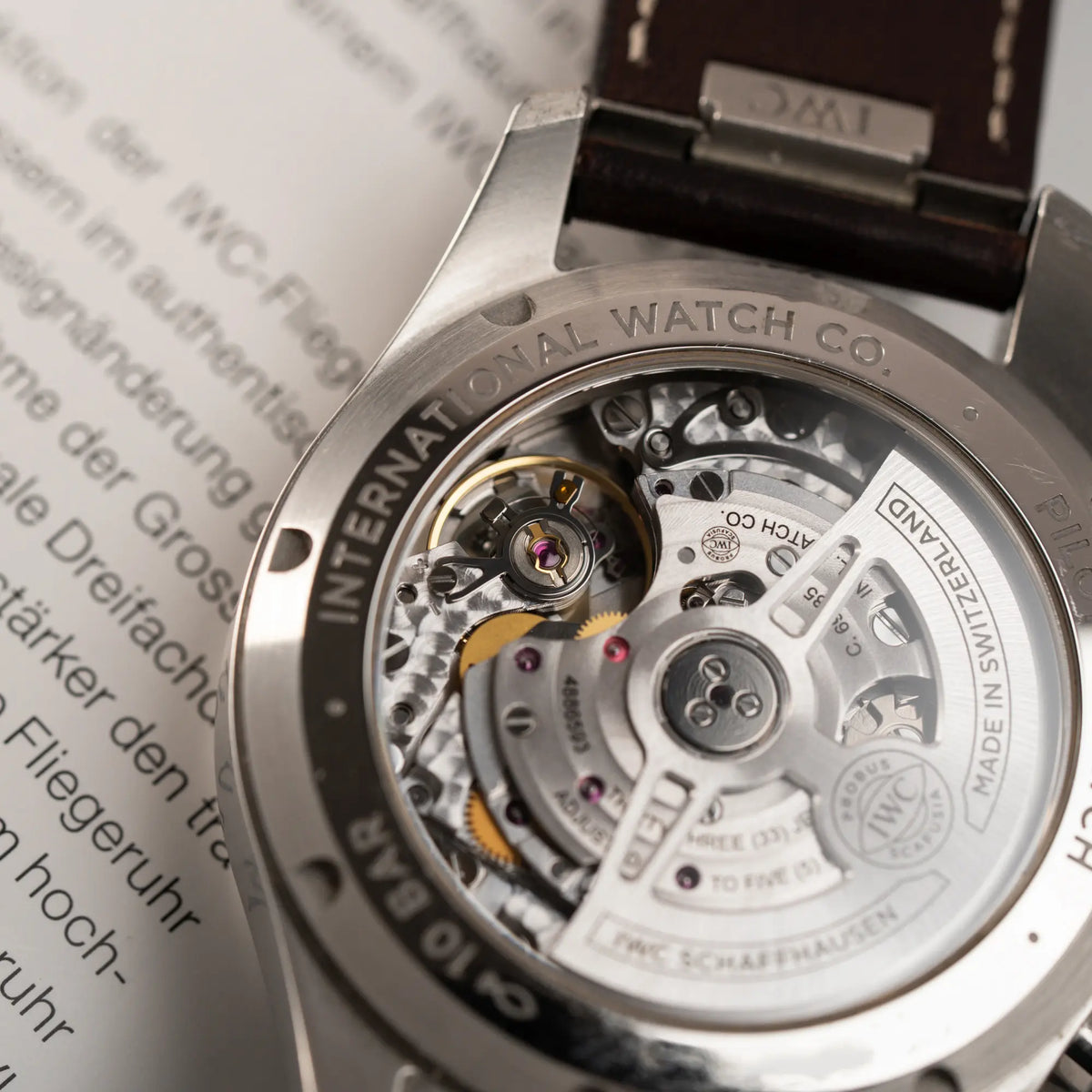 Produktfotografie des verschraubten Gehäusebodens mit Sichtglas von dem IWC Pilot 41 Chronographs IW388103 mit grünem Zifferblatt an einem braunen Lederband
