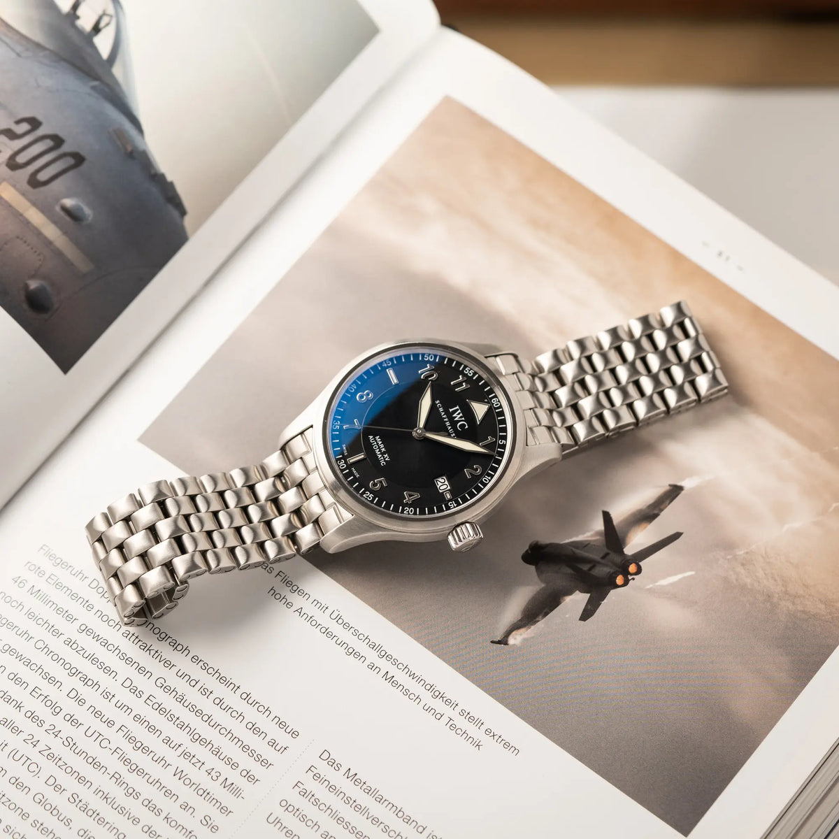 IWC Pilot Fliegeruhr Mark 15 der Referenz IW325312 aus 2005 mit dem schwarzen Zifferblatt an dem passenden, originalen 5-gliedrigen Stahlband liegt auf eine Buch