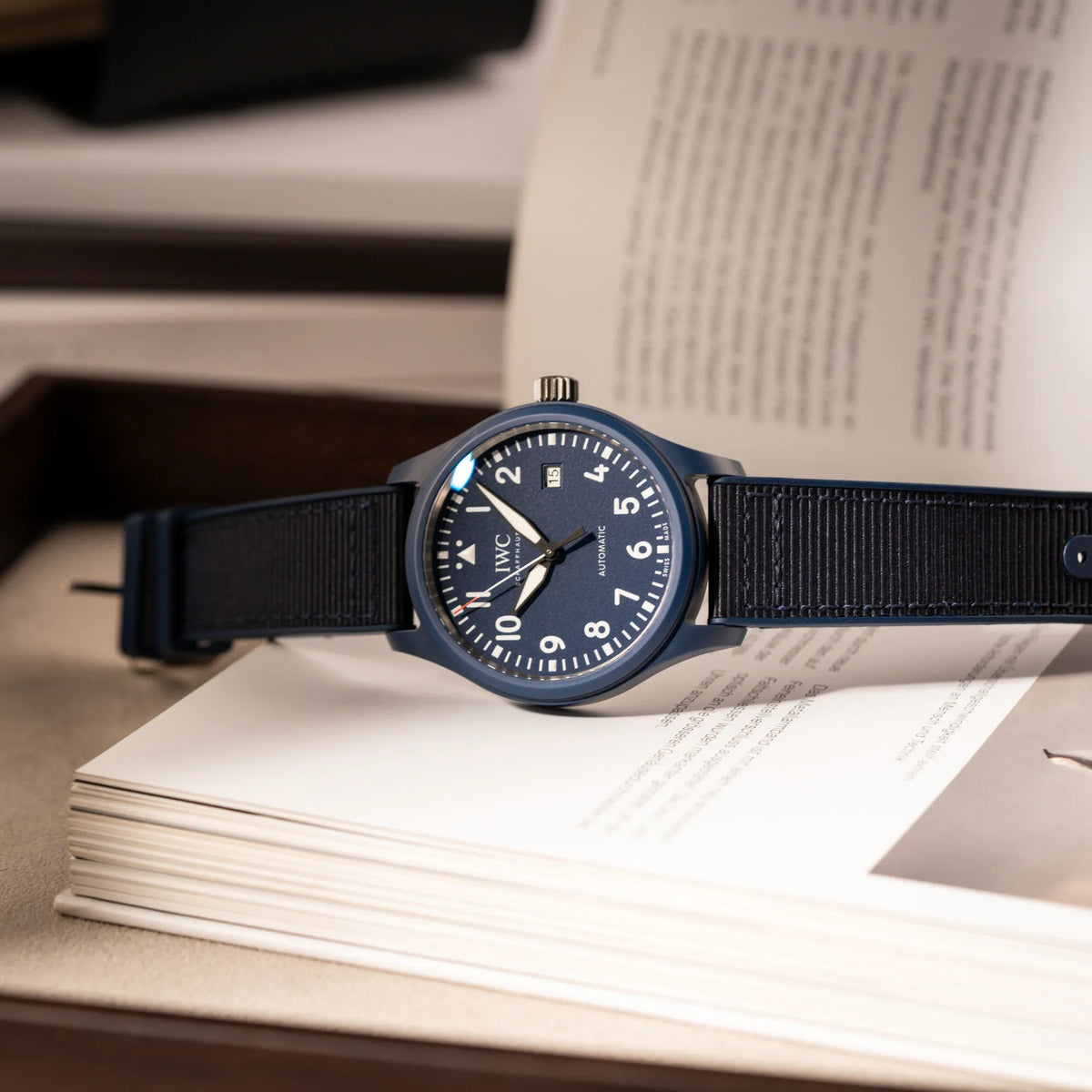 Produktfotografie der seitlich liegenden, limitierten IWC Pilot's Watch IW328101 "Laureus Sport for Good" mit blauem Keramik-Gehäuse