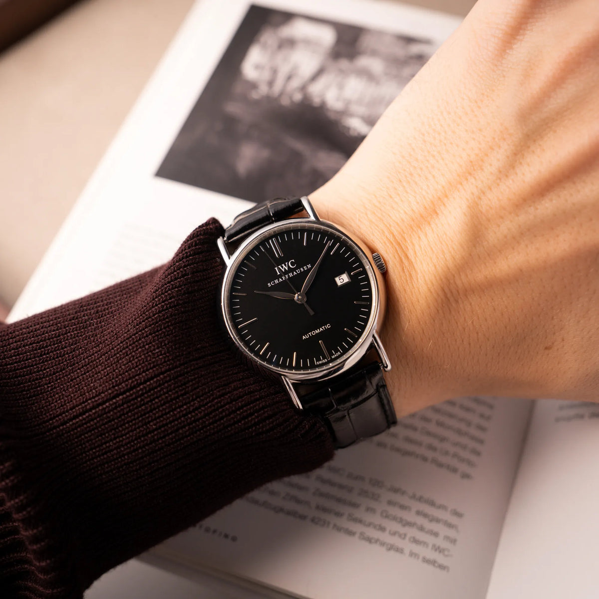 Mann trägt die IWC Portofino Automatik IW356305 Armbanduhr mit minimalistischen, schwarzem Zifferblatt mit Stichindizes am schwarzen Lederband an seinem Handelenk
