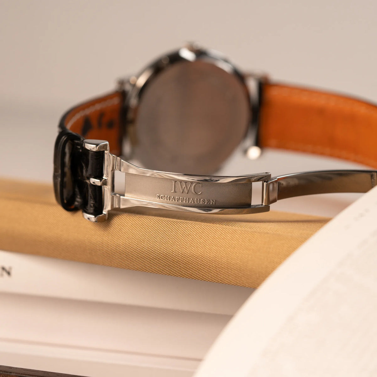 Produktfotografie zeigt das IWC Logo der IWC Portofino Automatik IW356305 Armbanduhr mit minimalistischen, schwarzem Zifferblatt mit Stichindizes am schwarzen Lederband