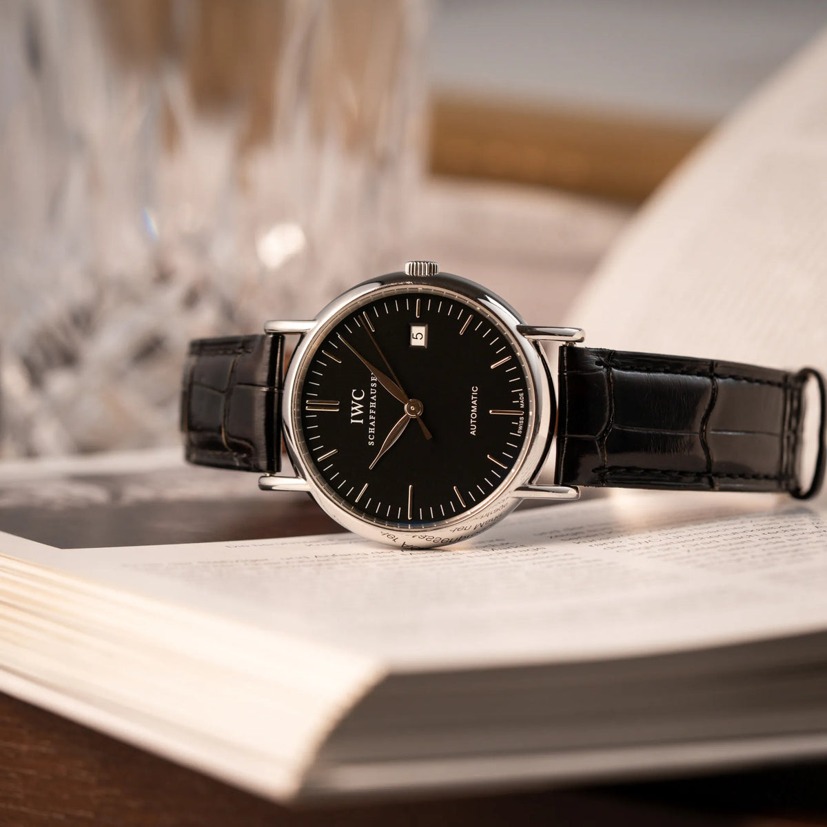 Produktfotografie als Titelbild für die IWC Portofino Automatik IW356305 Armbanduhr mit minimalistischen, schwarzem Zifferblatt mit Stichindizes am schwarzen Lederband
