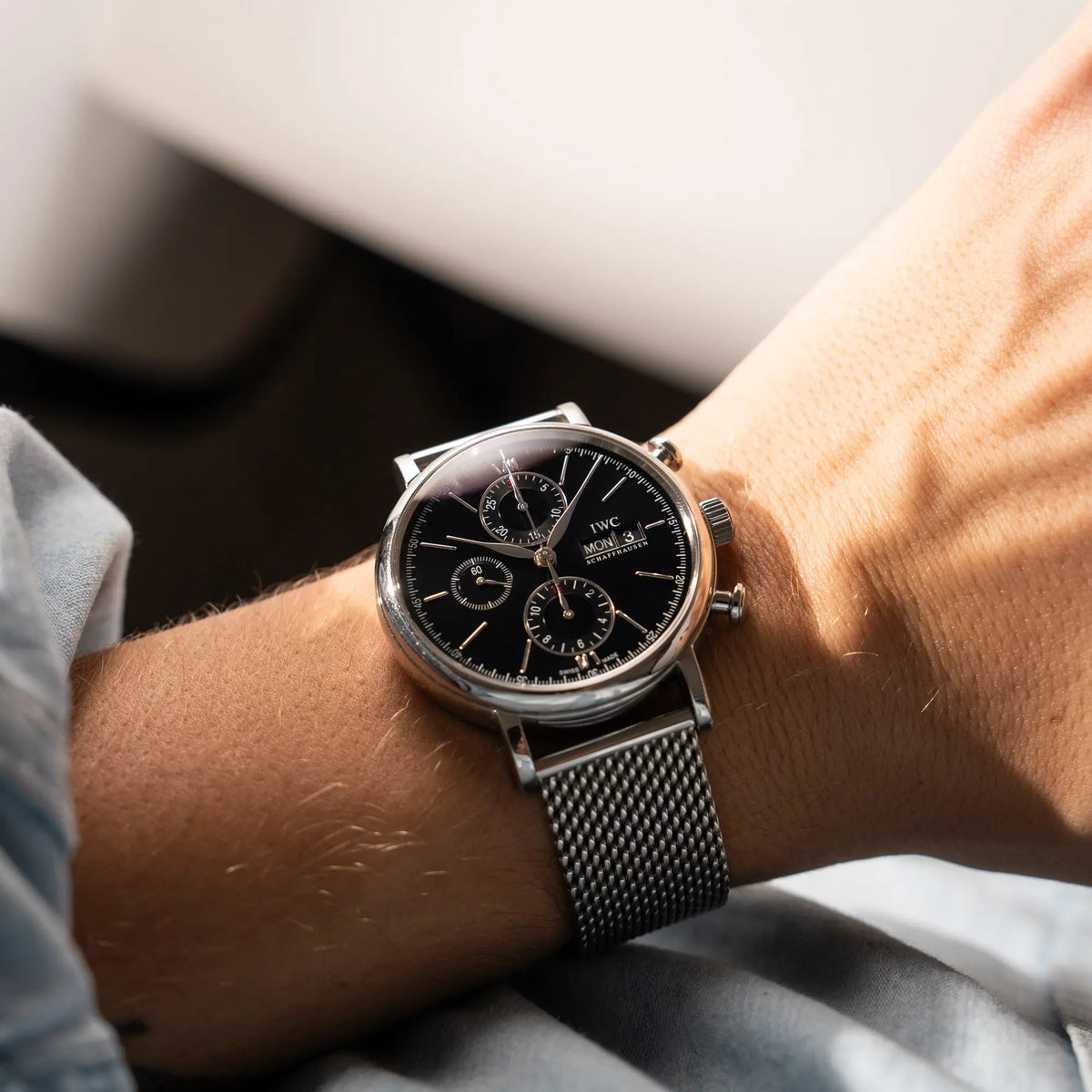 Mann trägt den IWC Portofino Chronograph der Referenz IW391002 mit schwarzem Zifferblatt an einem Mesh-Armband an seinem Handgelenk
