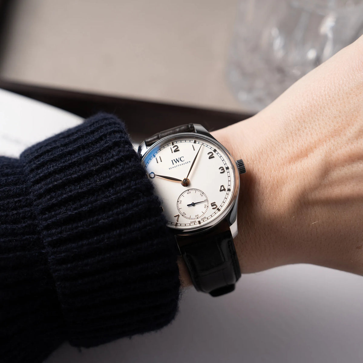 IWC Portugieser 40 Automatik IW358303 mit weißem Zifferblatt und roségoldenen Zeiger- und Index-Details am schwarzen Lederband getragen an einem Männerhandgelenk