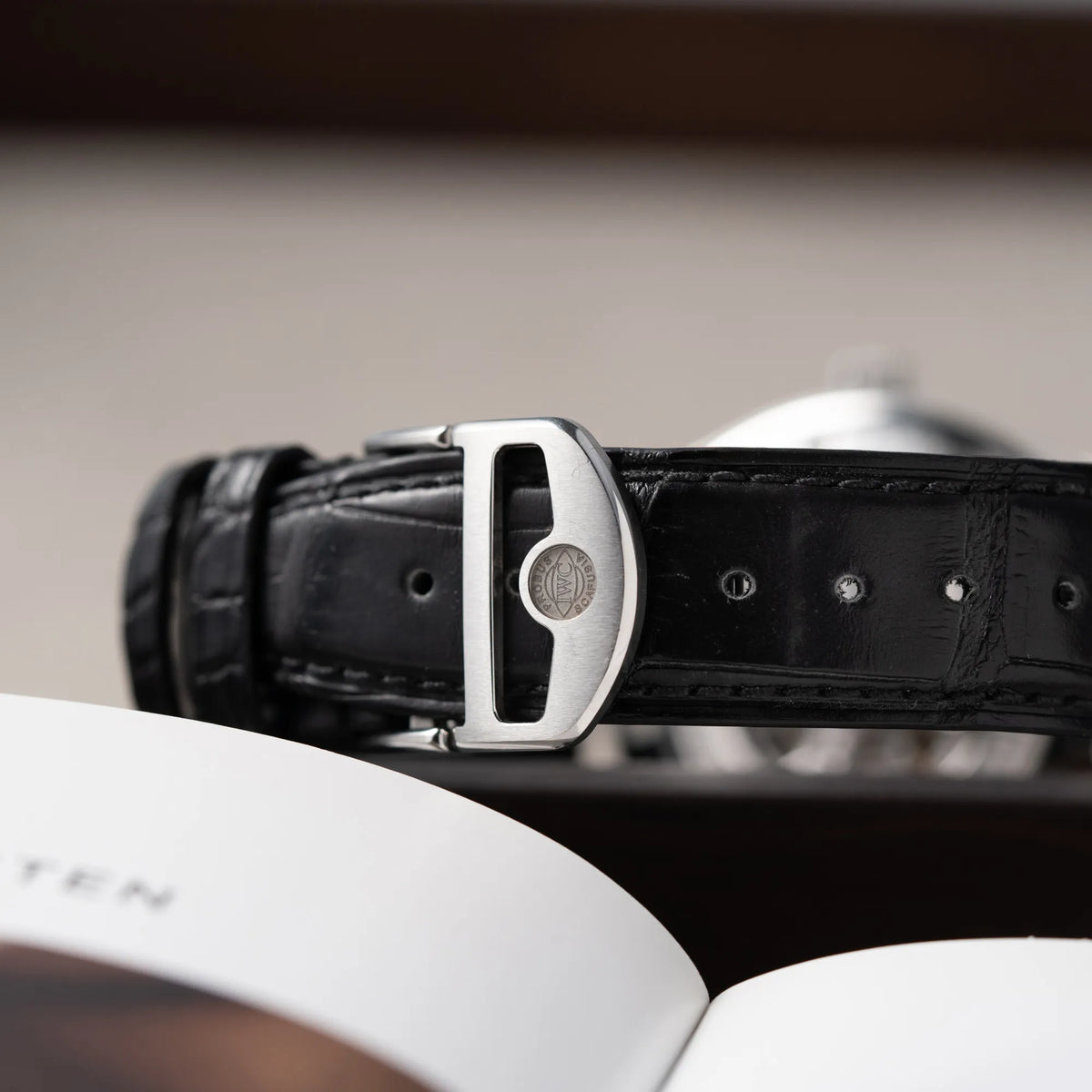 Detailaufnahme der geschlossenen Faltschließe an der IWC Portugieser 40 Automatik IW358303 mit weißem Zifferblatt und roségoldenen Zeiger- und Index-Details am schwarzen Lederband