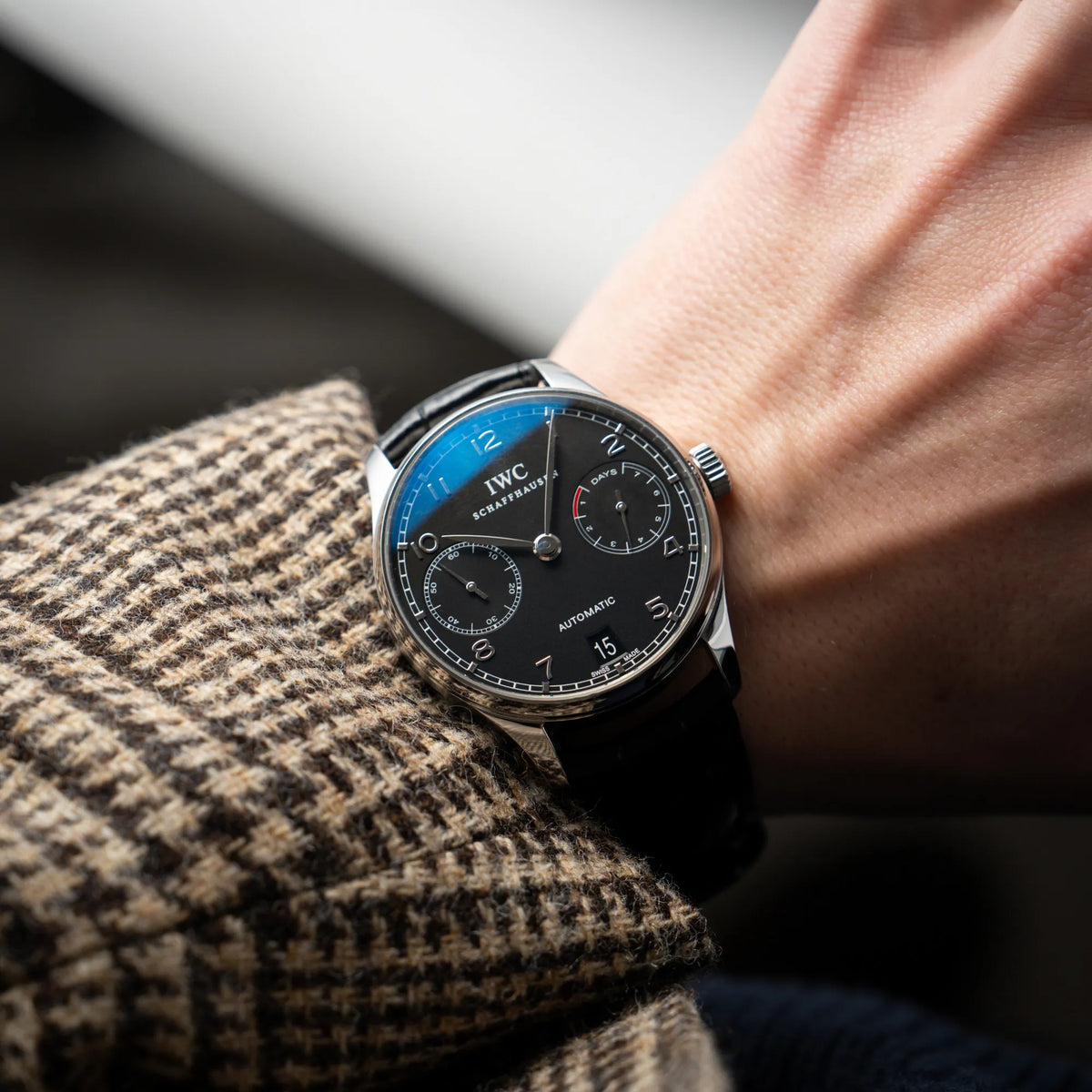 Mann trägt den IWC Portugieser 7 Days IW500109 mit schwarzem Zifferblatt am schwarzen Lederband an seinem Handgelenk