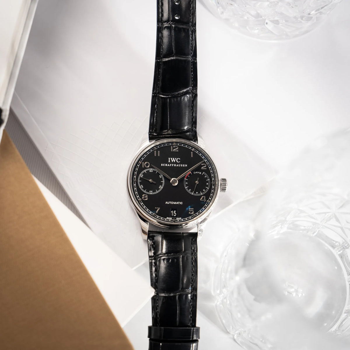 Produktfotografie als Titelbild für die IWC Portugieser 7 Days IW500109 mit schwarzem Zifferblatt am schwarzen Lederband