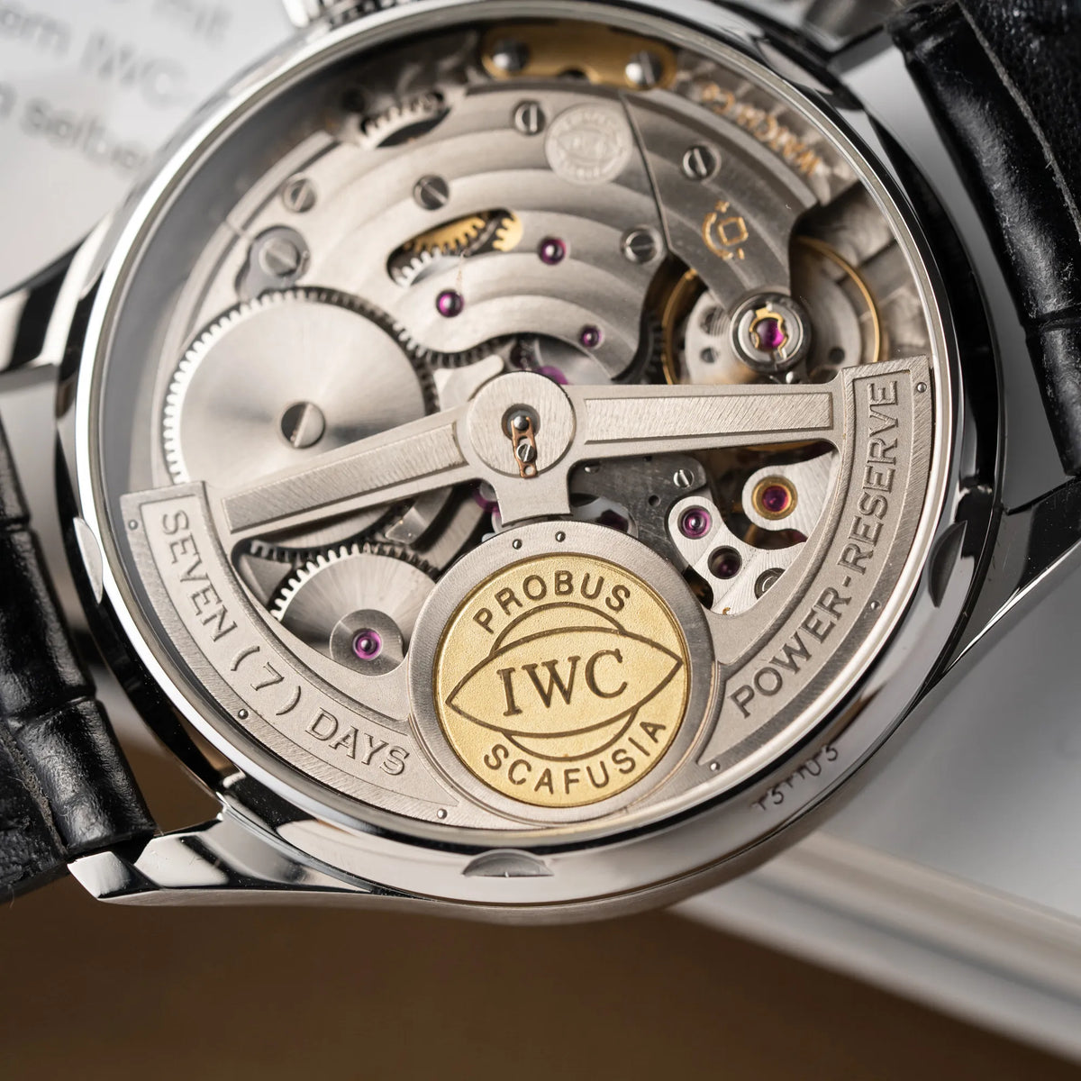 Detailaufnahme des Uhrwerks durch den Sichtboden der IWC Portugieser 7 Days IW500109 mit schwarzem Zifferblatt am schwarzen Lederband