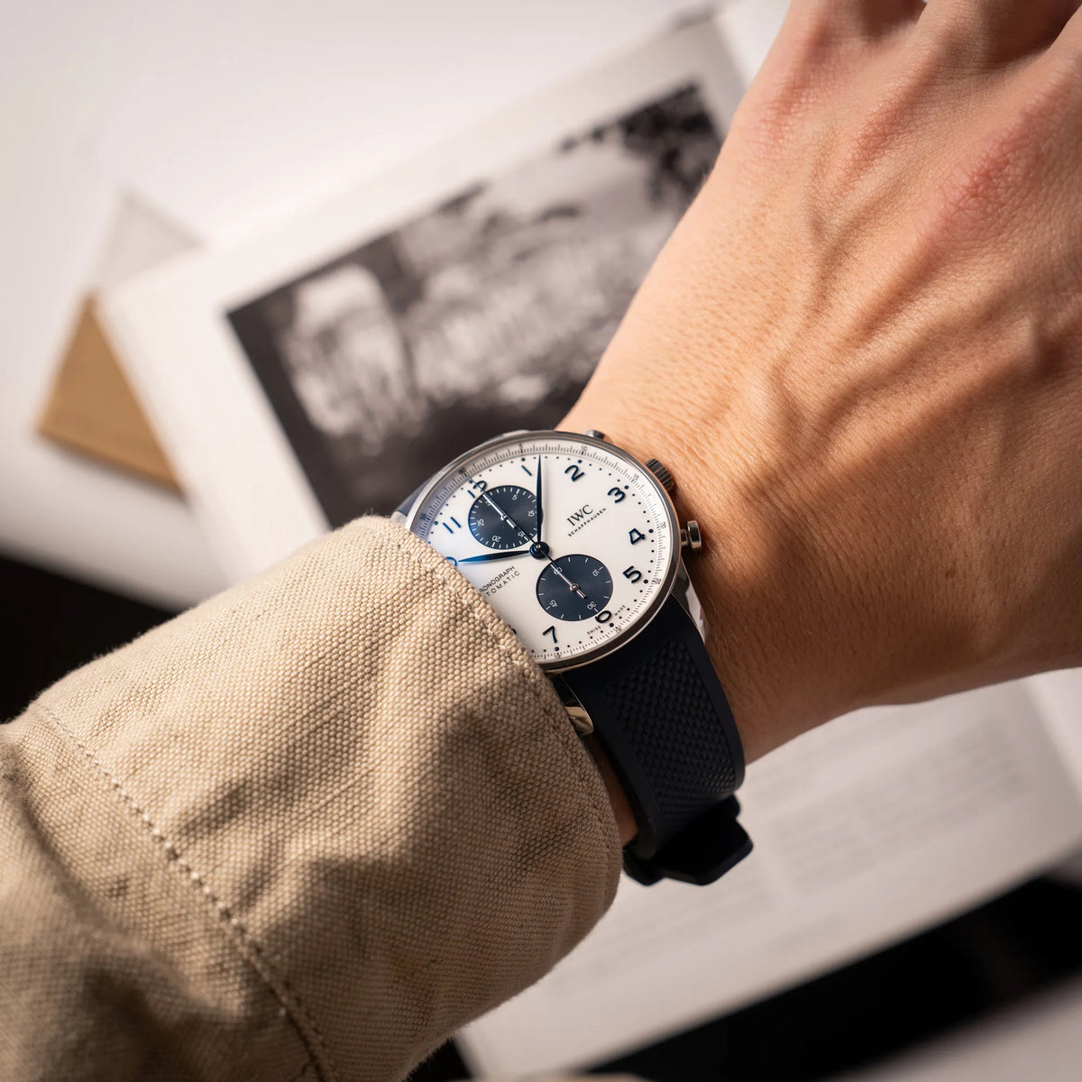 Mann trägt die IWC Portugieser Chronograph 41 der Referenz IW371620 mit weißem Zifferblatt und dunkelblauen Totalisatoren am passenden dunkelblauen Kautschukarmband an seinem Handgelenk