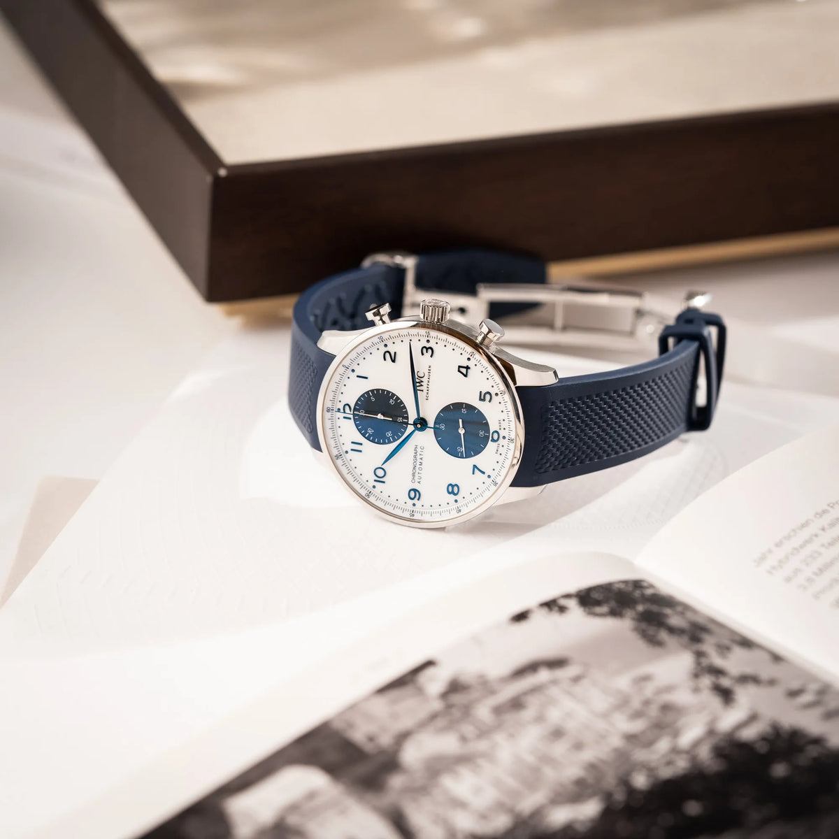 Produktfotografie der IWC Portugieser Chronograph 41 der Referenz IW371620 mit weißem Zifferblatt und dunkelblauen Totalisatoren am passenden dunkelblauen Kautschukarmband