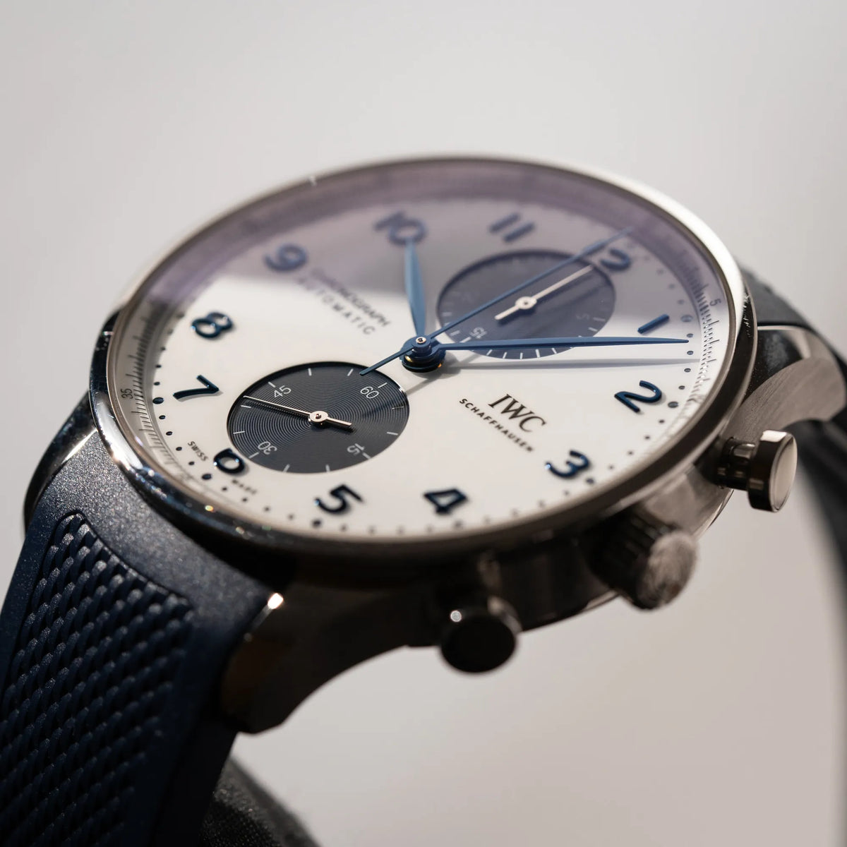 Künstlerische Produktfotografie der IWC Portugieser Chronograph 41 der Referenz IW371620 mit weißem Zifferblatt und dunkelblauen Totalisatoren am passenden dunkelblauen Kautschukarmband