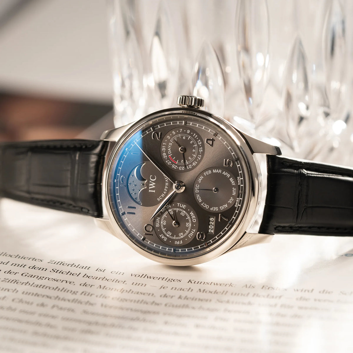 Produktfotografie der seitlich auf dem Gehäuse liegenden IWC Portugieser Ewiger Kalender IW502307 mit 44m Weißgold-Gehäuse und anthrazit-farbenem Zifferblatt