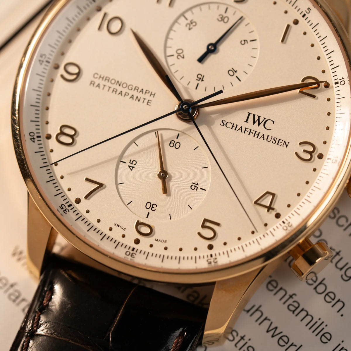 Detailaufnahme des IWC Portugieser Rattrapante Doppel-Chronograph IW3712 aus 18k Roségold mit weißem Zifferblatt am braunen Lederband mit Fokus auf den zwei Chronograph-Zeigern