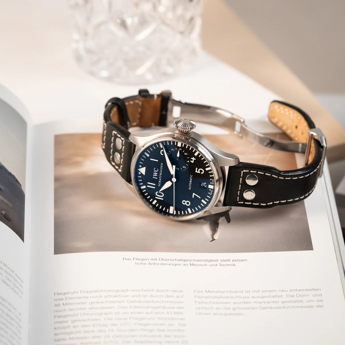 Produktfotografie der seitlich auf dem Gehäuse liegenden IWC Big Pilot 46 Armbanduhr der Referenz IW500401 mit schwarzem Zifferblatt und der Power-Reserve-Anzeige bei 3 Uhr
