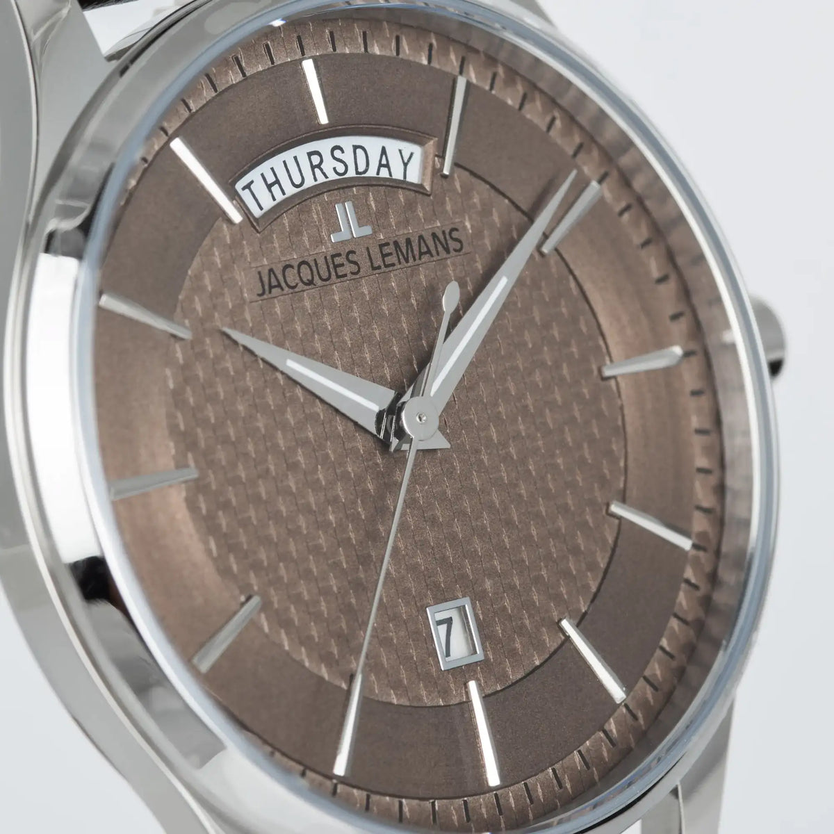 Leicht schräge Ansicht der Jacques Lemans 1-2193K Derby Armbanduhr mit Tages und Datumsanzeige, welche farblich abgestimmt ist durch ein bronzefarbenes Zifferblatt und ein braunes Lederband