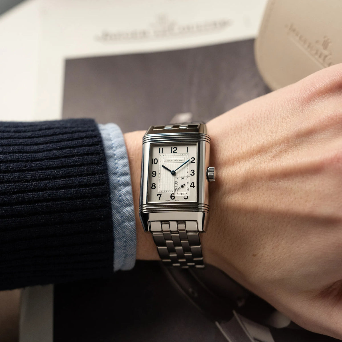 Mann trägt die Jaeger LeCoultre Grand Reverso 8 Armbanduhr am Stahlband mit silbernem Zifferblatt an seinem Handgelenk