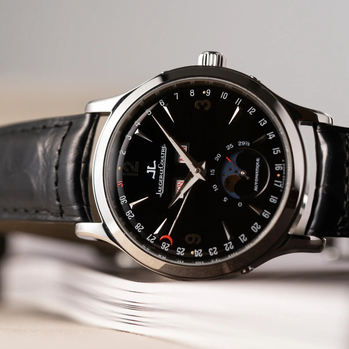 Detailaufnahme der seitlich liegenden Jaeger-LeCoultre Master Control Moonphase Calendar mit schwarzem Zifferblatt am schwarzen Lederband