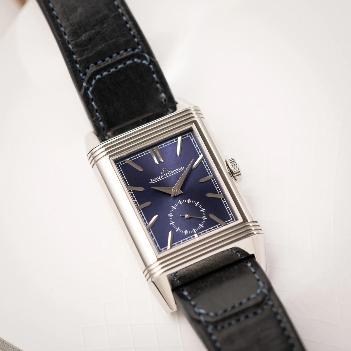 Detailaufnahme des Uhrengehäuses von der Jaeger-LeCoultre Reverso Duoface Q3988482 mit blauem Zifferblatt und weißem Night-and-Day-Zifferblatt am schwarzen Lederband zeigt das blaue Sonnenschliff-Zifferblatt