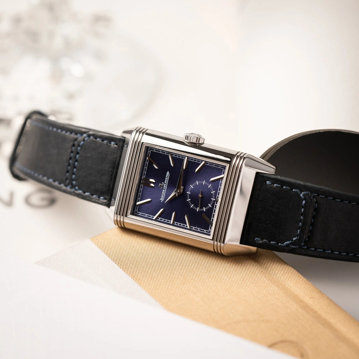 Produktfotografie der Jaeger-LeCoultre Reverso Duoface Q3988482 mit blauem Zifferblatt und weißem Night-and-Day-Zifferblatt am schwarzen Lederband zeigt das blaue Zifferblatt