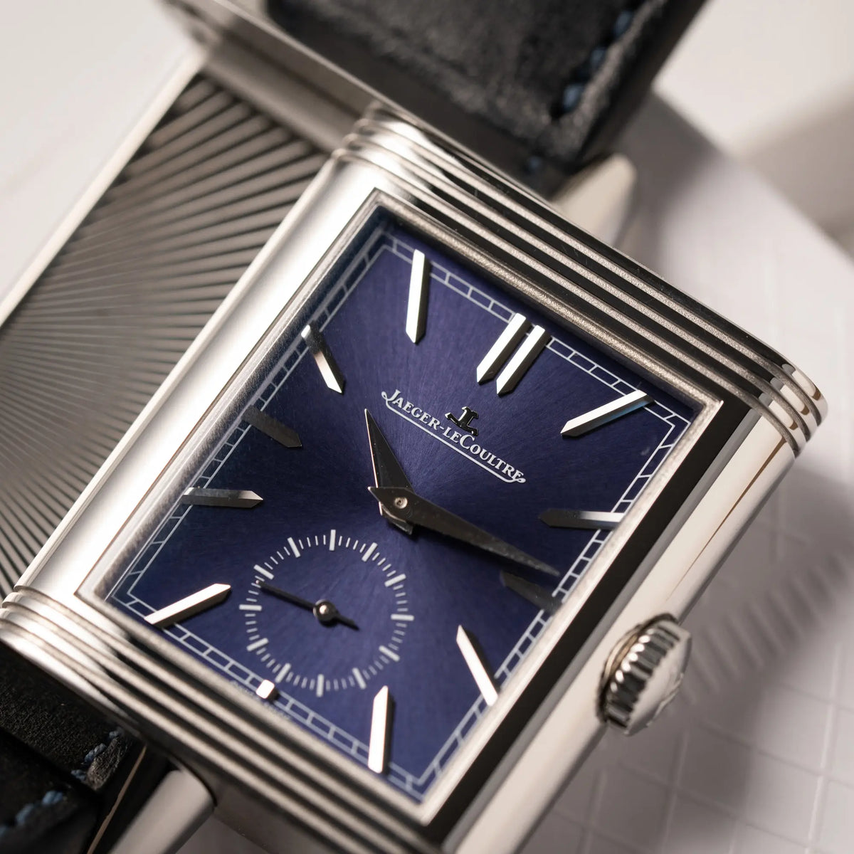 Produktfotografie als Titelbild für dieJaeger-LeCoultre Reverso Duoface Q3988482 mit blauem Zifferblatt und weißem Night-and-Day-Zifferblatt am schwarzen Lederband