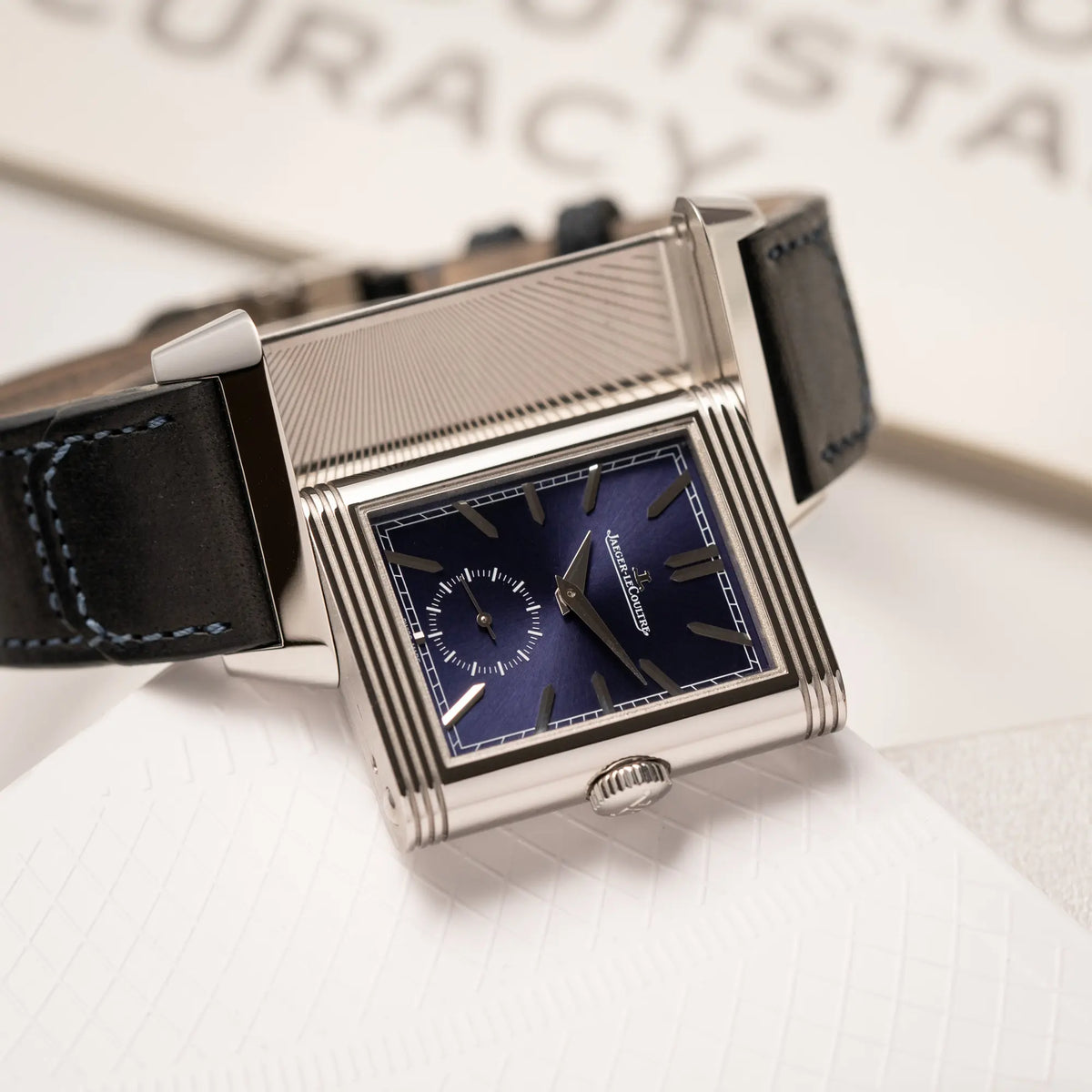 Jaeger-LeCoultre Reverso Duoface Q3988482 mit blauem Zifferblatt und weißem Night-and-Day-Zifferblatt am schwarzen Lederband mit betätigtem Reverso-Mechanismus zeigt den blauen Sonnenschliff des Zifferblatts