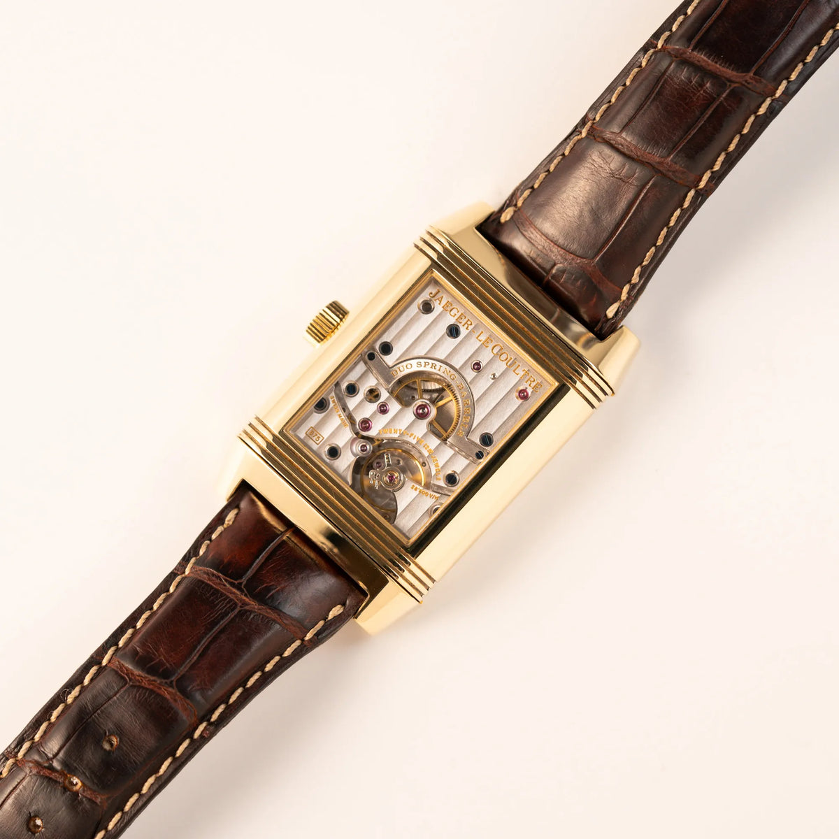Detailaufnahme der Jaeger-LeCoultre Reverso Grande Date der Referenz 240.1.15 mit einem Gelbgold-Gehäuse am braunen Lederband zeigt das Sichtglas mit Blick auf das Uhrwerk nach umgedrehten Reverso-Mechanismus