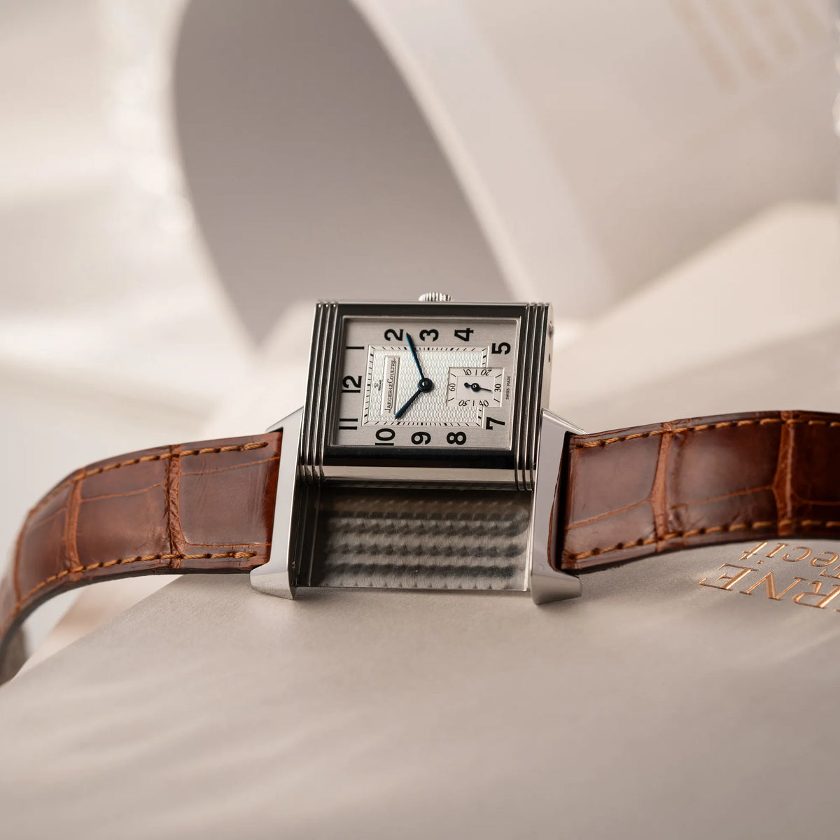 Jaeger-LeCoultre Reverso Grande Taille der Referenz 270.8.62 mit einem teil-guillochiertem, silberfarbenem Zifferblatt an einem braunem Lederband, während der Reverso-Mechanismus in Benutzung ist