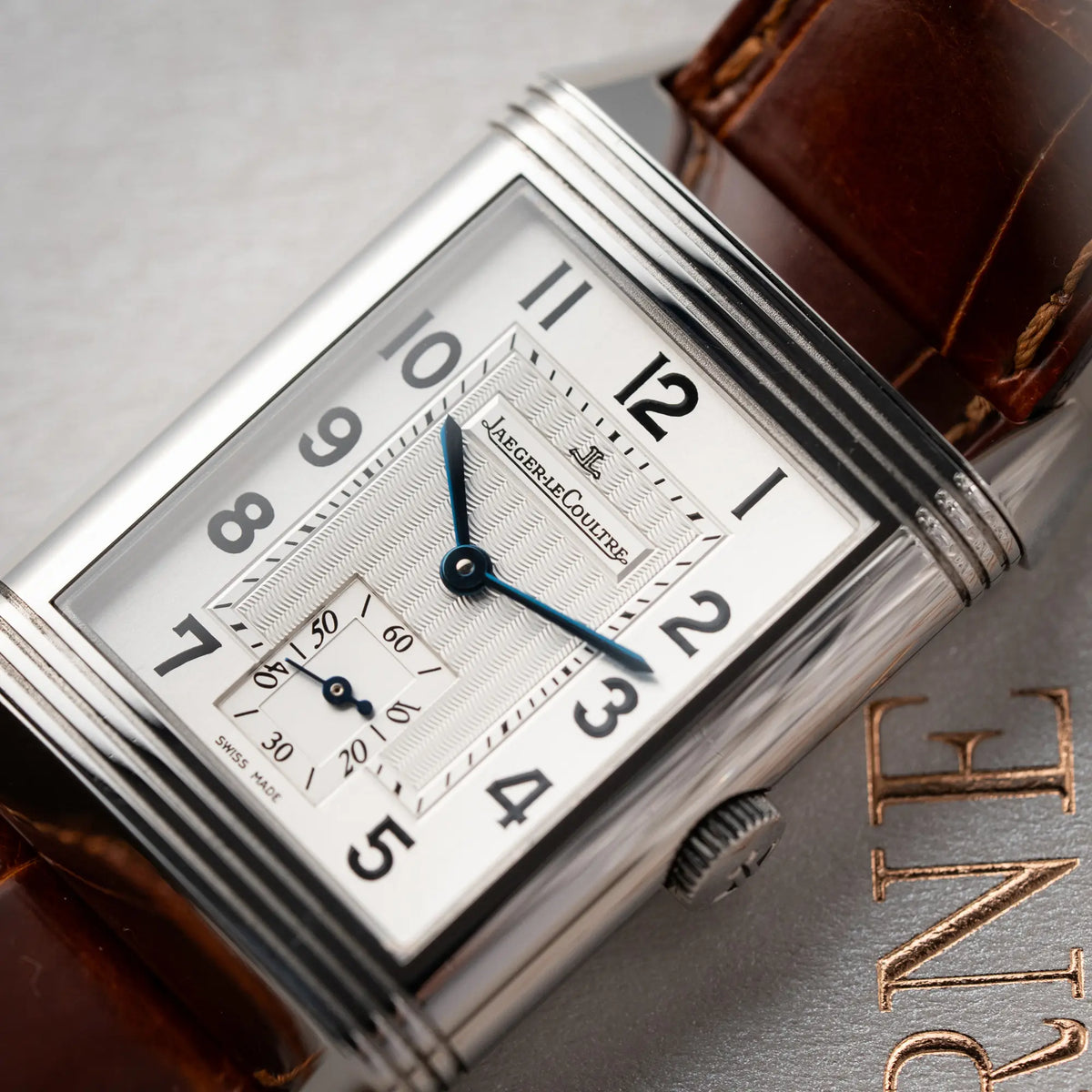 Detailaufnahme zeigt das Zifferblatt im Detaul von der Jaeger-LeCoultre Reverso Grande Taille der Referenz 270.8.62 mit einem teil-guillochiertem, silberfarbenem Zifferblatt an einem braunem Lederband