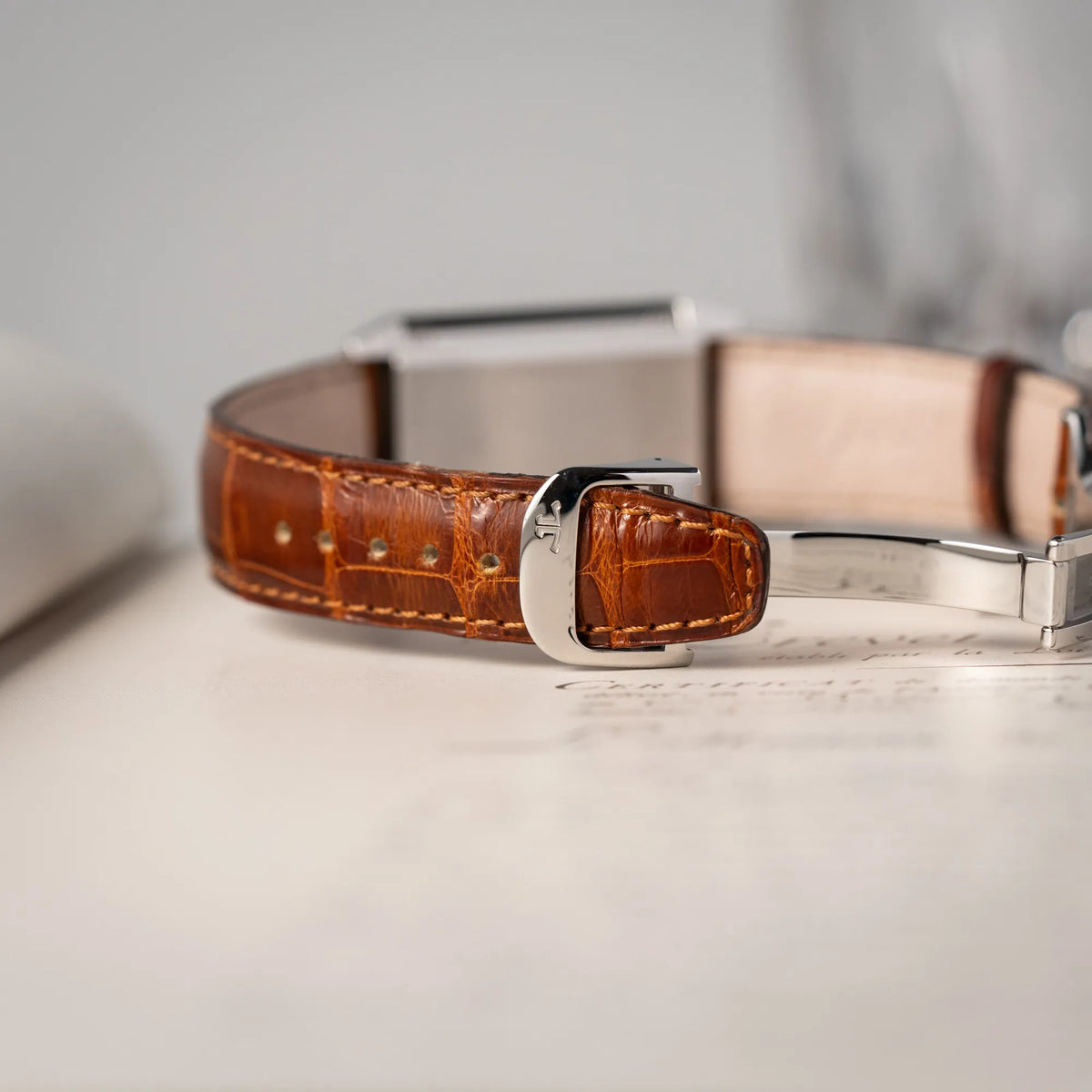 Detailaufnahme der JLC-Schliesse von der Jaeger-LeCoultre Reverso Grande Taille der Referenz 270.8.62 mit einem teil-guillochiertem, silberfarbenem Zifferblatt an einem braunem Lederband