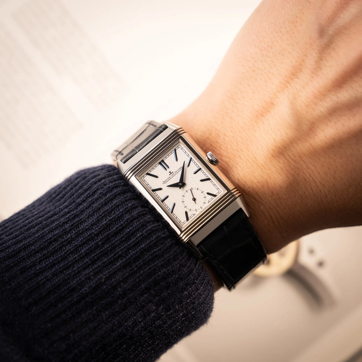 Wristshot mit der Jaeger-LeCoultre Reverso Tribute Duoface Q3908420 mit weißem Zifferblatt an einem dunkelblauen Lederband