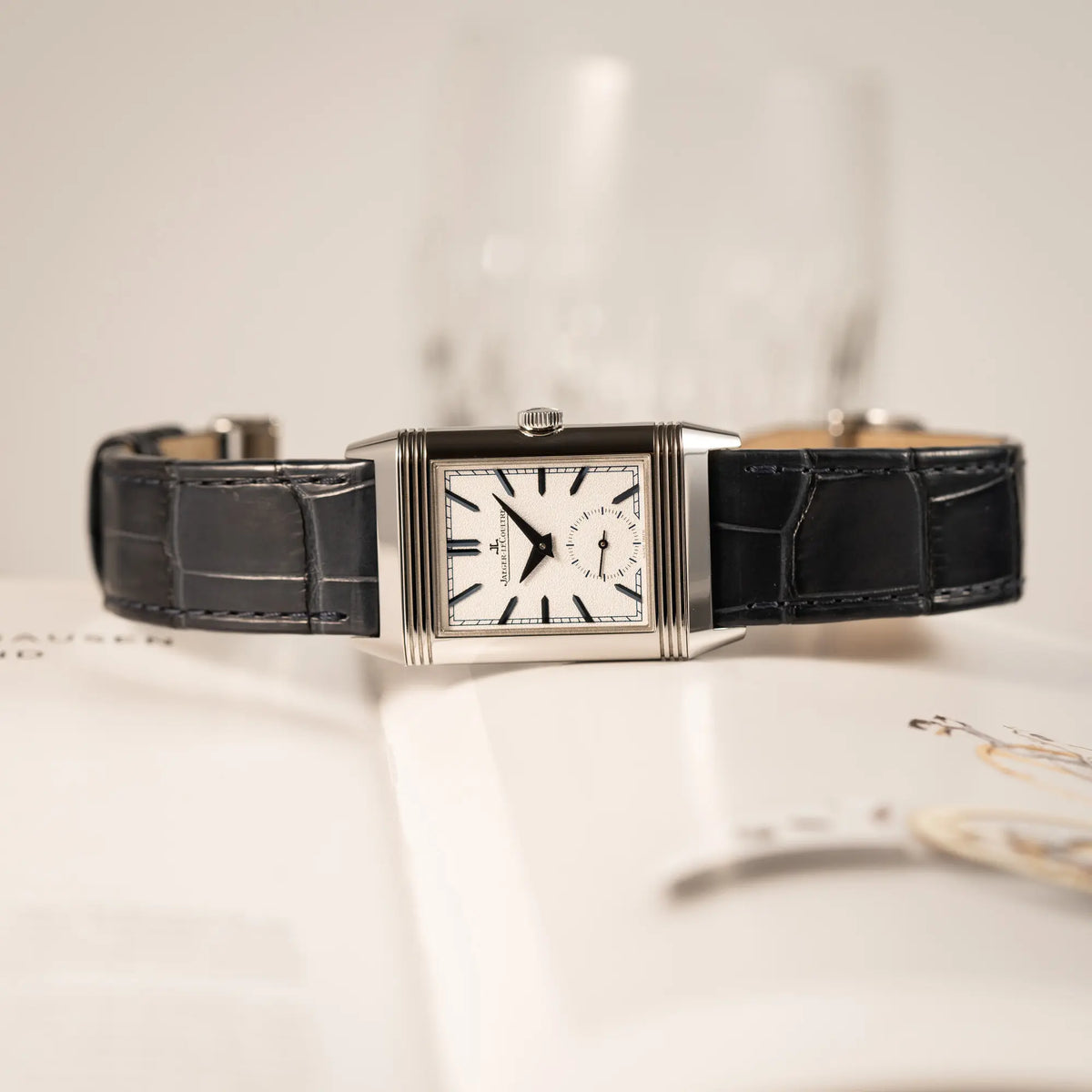 Produktfotografie der seitliche auf dem Gehäuse liegenden Jaeger-LeCoultre Reverso Tribute Duoface Q3908420 an einem dunkelblauen Lederband zeigt das weiß-silberne Zifferblatt