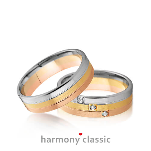 Produktfotografie des Trauringpaars Harmony Classic in Rosegold, Gelbgold und Weißgold mit jeweils einem Diamanten pro Goldstreifen im Damenring