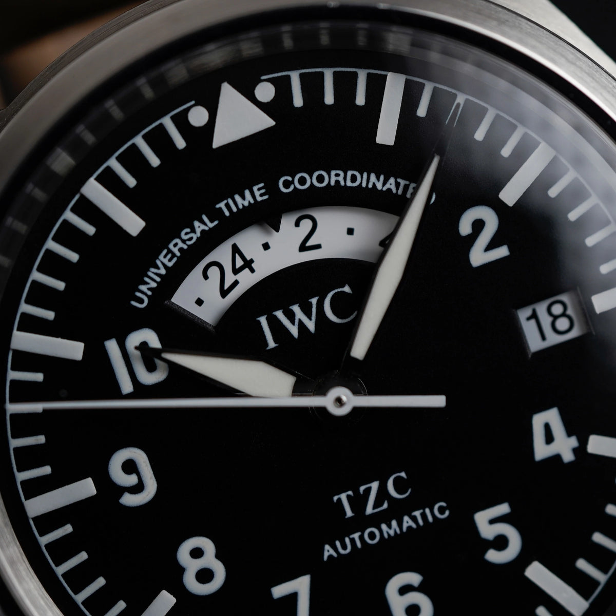 Makroaufnahme des schwarzen Zifferblatts mit GMT-Funktion der IWC Schaffhausen Pilot Fliegeruhr UTC Spitfire mit der Referenz IW3251 und Datumsanzeige