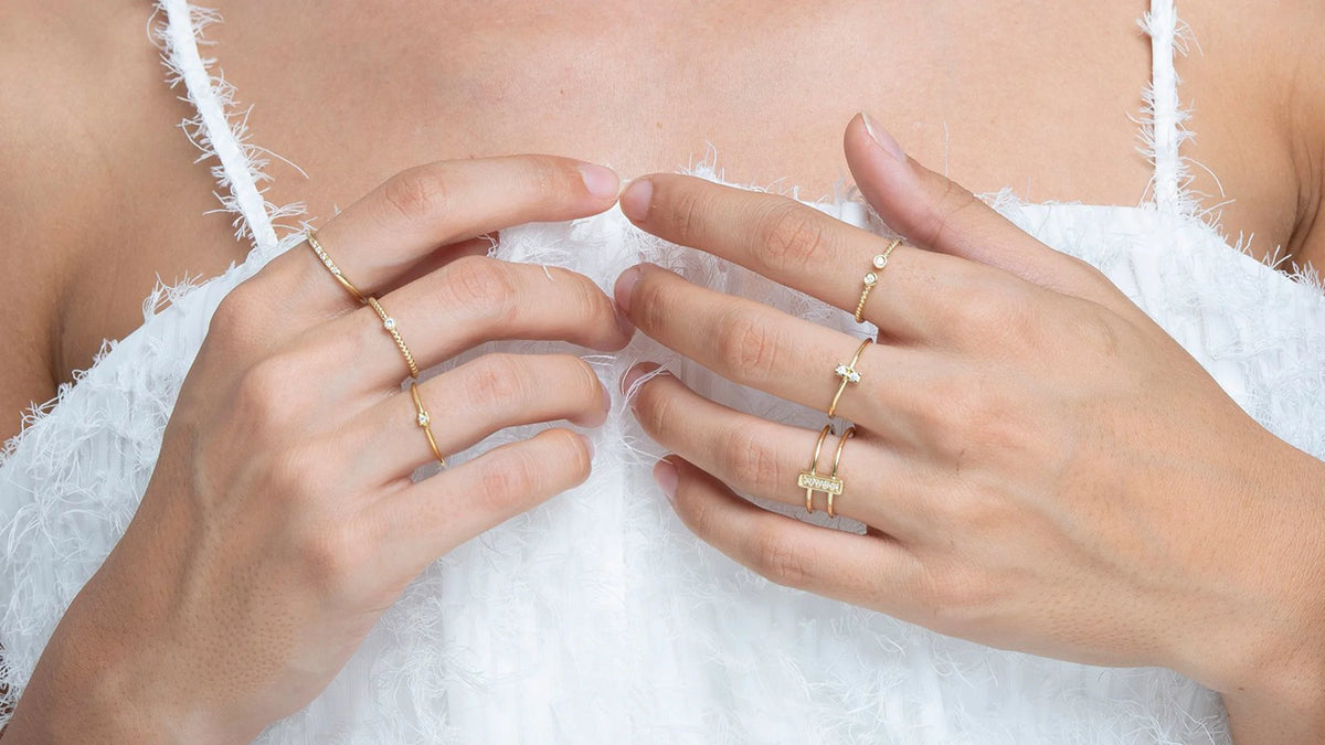 Frau trägt an beiden Händen jeweils einen verschiedenen Ring an Ringfinger, Mittelfinger und Zeigefinger von Marina Garcia in 18 Karat Gelbgold