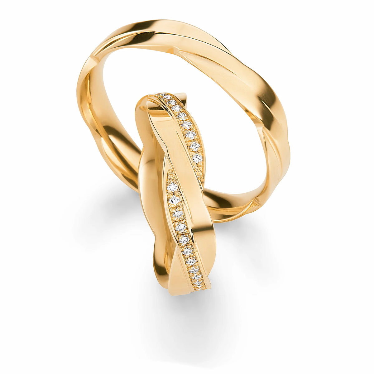 Produktfotografie des gelbgoldenen Max Kemper Trauringpaars mit einer einzigartigen Form der Ringschiene, die an zwei ineinander verschmelzende Ringe erinnert, mit einer polierten Oberfläche und speziell für den Damenring eingefassten Diamant-Schienen