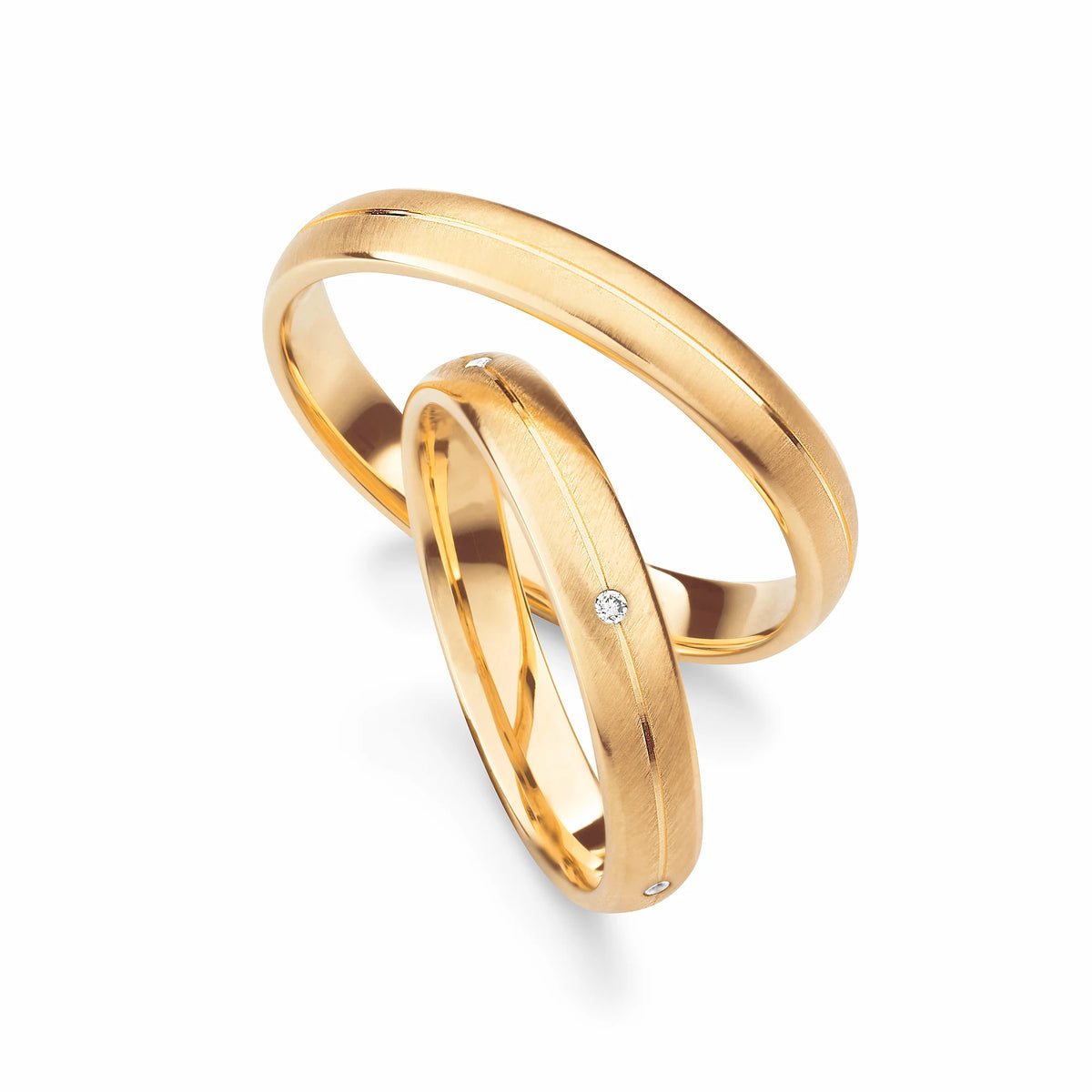 Produktfotografie des gelbgoldenen Max Kemper Trauringpaars mit einer gebürsteten Oberflächenstruktur und einer zentral eingravierten Nut und Diamanten im Damenring