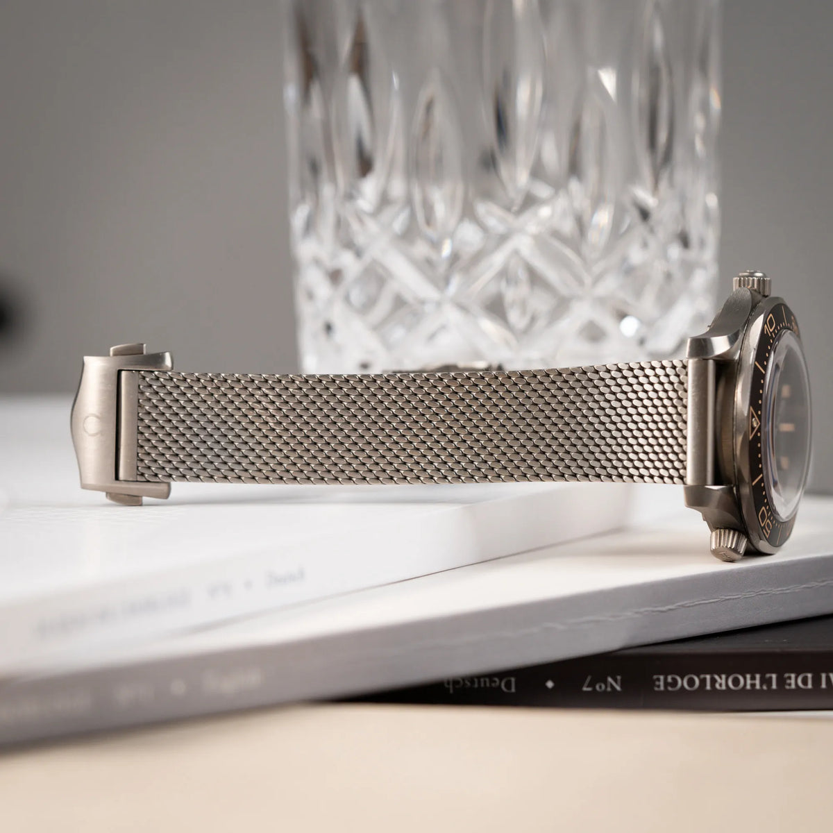 Produktfotografie der Omega Seamaster 300m Diver No Time To Die Limited Edition aus Titan mit braunem Zifferblatt mit Fokus auf dem Zustand des Milanese-Armbands aus Titan