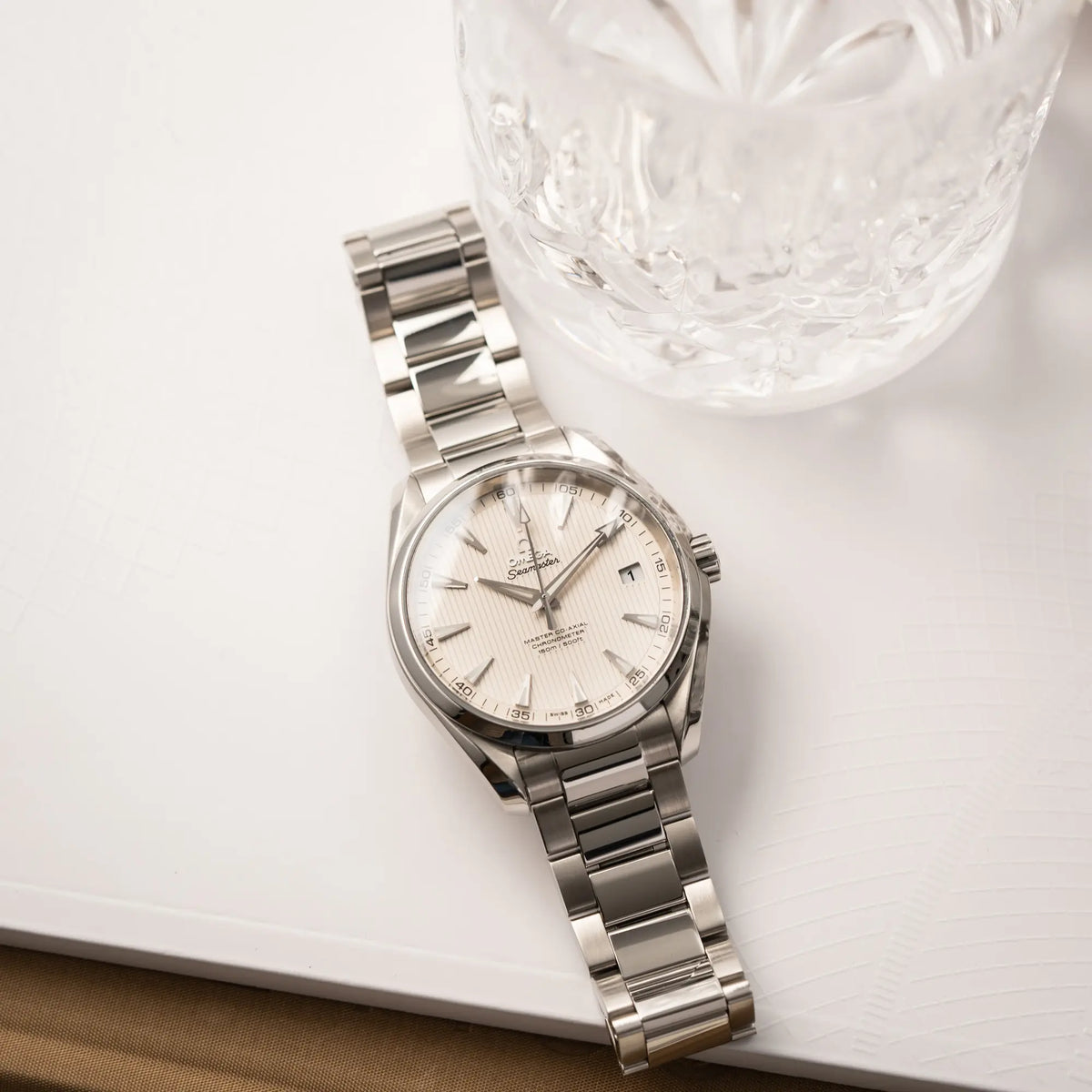Produktfotografie der Omega Seamaster Aqua Terra 150M mit 41mm-Gehäuse und einem weißen Zifferblatt mit vertikal verlaufenden Linien