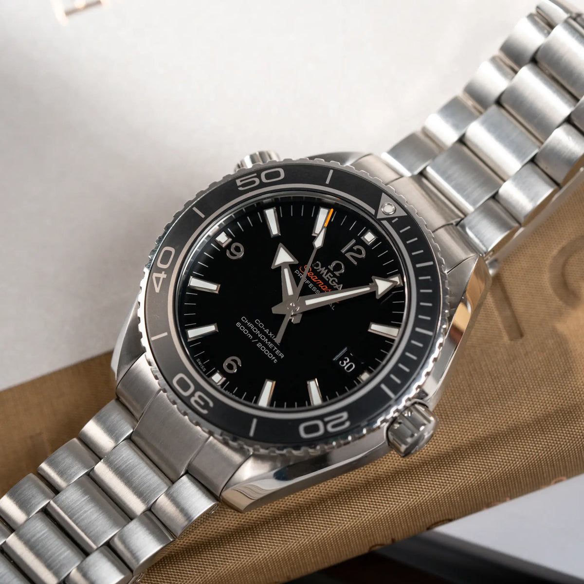 Produktfotografie der Omega Seamaster Planet Ocean 232.30.46.21.01.001 mit 45mm Gehäuse und schwarzem Zifferblatt mit orangen Details mit Fokus auf der schwarzen/anthraziten Lünette