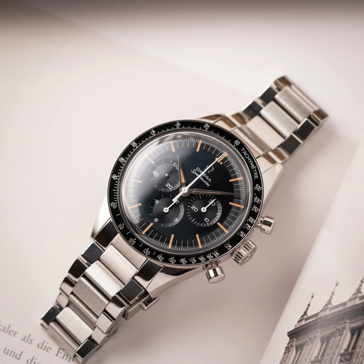 Produktfotografie als Titelbild für die Omega Speedmaster FOIS der Referenz 310.30.40.50.06.001 mit dem dunkelblauen Zifferblatt mit dunkel-beigen Indizes im Vintage-Look und einem vom Standard-Modell abgeänderten Stahl-Armband, was beides an das klassische Speedy-Modell erinnert