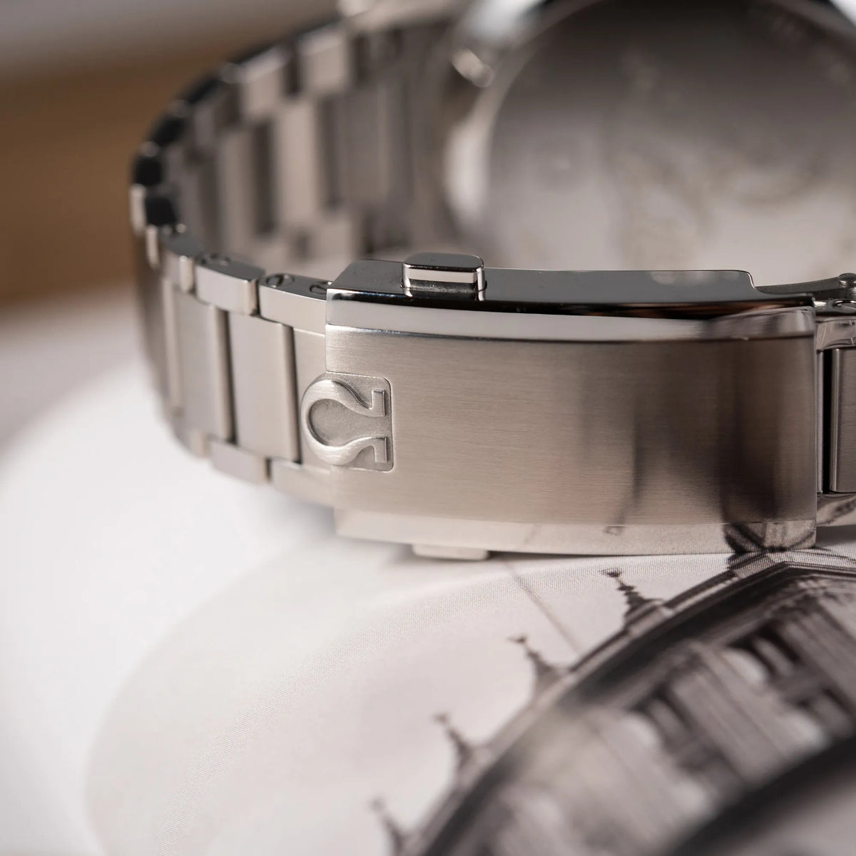 Detailaufnahme der Stahl-Faltschliesse mit Omega-Logo von der Omega Speedmaster FOIS der Referenz 310.30.40.50.06.001 mit dem dunkelblauen Zifferblatt mit dunkel-beigen Indizes im Vintage-Look und einem vom Standard-Modell abgeänderten Stahl-Armband, was beides an das klassische Speedy-Modell erinnert