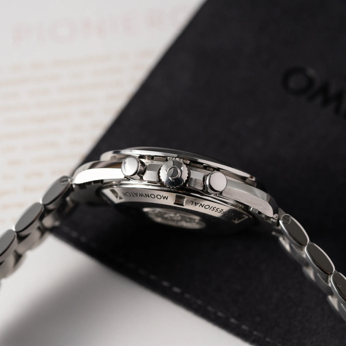 Produktfotografie der Omega Speedmaster Professional Moonwatch der Referenz 311.30.42.30.01.005 in einem 42mm-Gehäuse mit klassischem schwarzen Zifferblatt und verbautem Hesalitglas zeigt die seitliche Gehäuseflanke mit Blick auf die Aufzugskrone und die Chronograph-Drücker