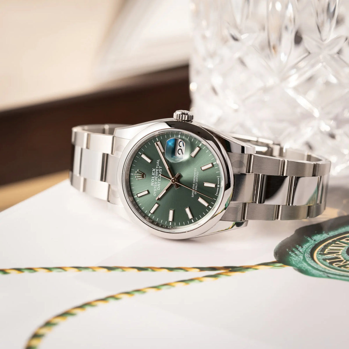 mit Stickern teil-verklebte Rolex Datejust 36 der Referenz 126200 mit glatter Lünette am Oyster-Stahlband mit dem Mint-Green-Zifferblatt liegt auf einem Rolex-Magazin