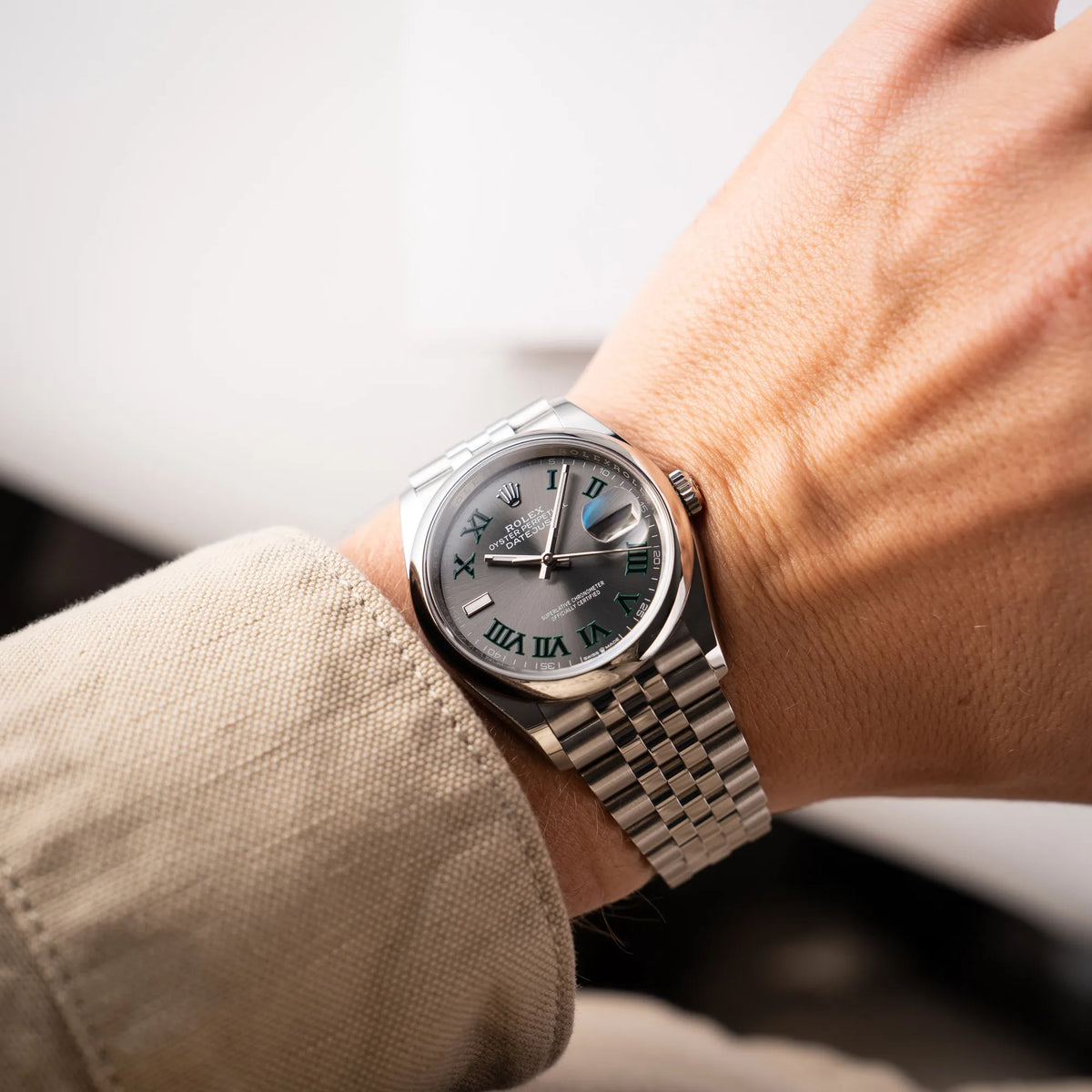 Mann trägt die Rolex Datejust 36 Wimbledon der Referenz 126200 mit glatter Lünette, anthrazitfarbenem Zifferblatt und schwarz-grünen, römischen Indizes am Jubillee-Armband für einen Wristshot an seinem Handgelenk
