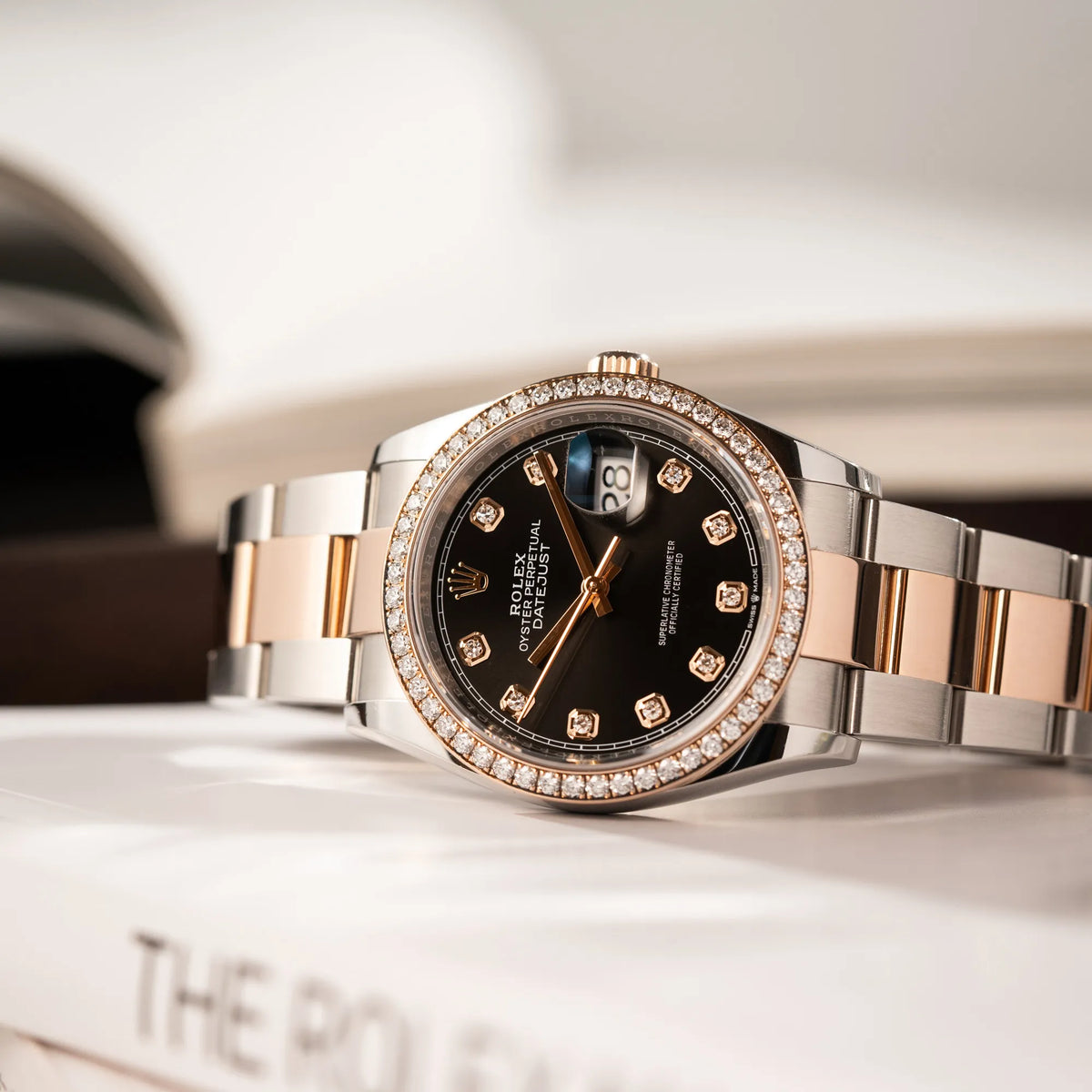Produktfotografie der seitlich auf dem Uhrengehäuse liegenden Rolex Datejust 36 126218RBR in Stahl-Roségold mit schwarzem Diamant-Zifferblatt und Diamant-Lünette im Factory-Besatz